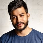 Close-up portrait of a handsome man with a beard in casual attire, smiling warmly.